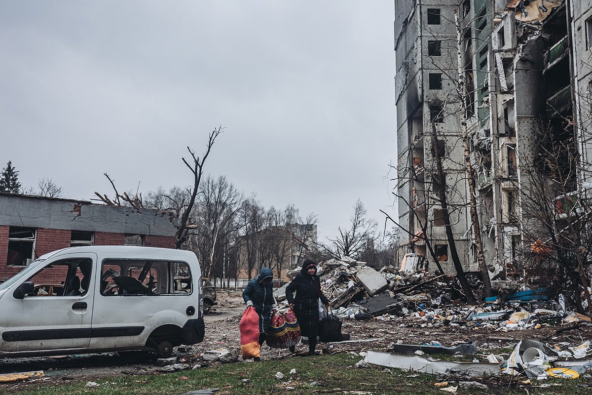Люди носят продукты возле разбомбленных зданий в Чернигове, 5 апреля 2022 года Фото: Diego Herrera Carcedo / Anadolu Agency / Getty Images