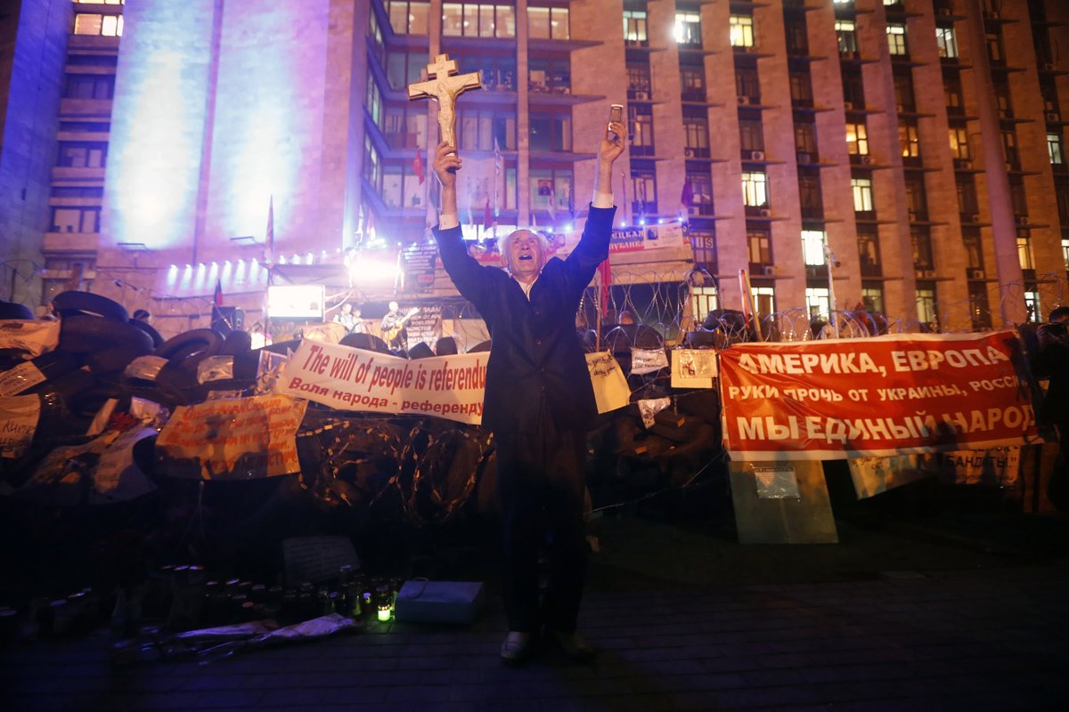 Мужчина держит крест, празднуя объявление результатов референдума в Донецке, 12 мая 2014 года .  Фото: Максим Шипенков / EPA