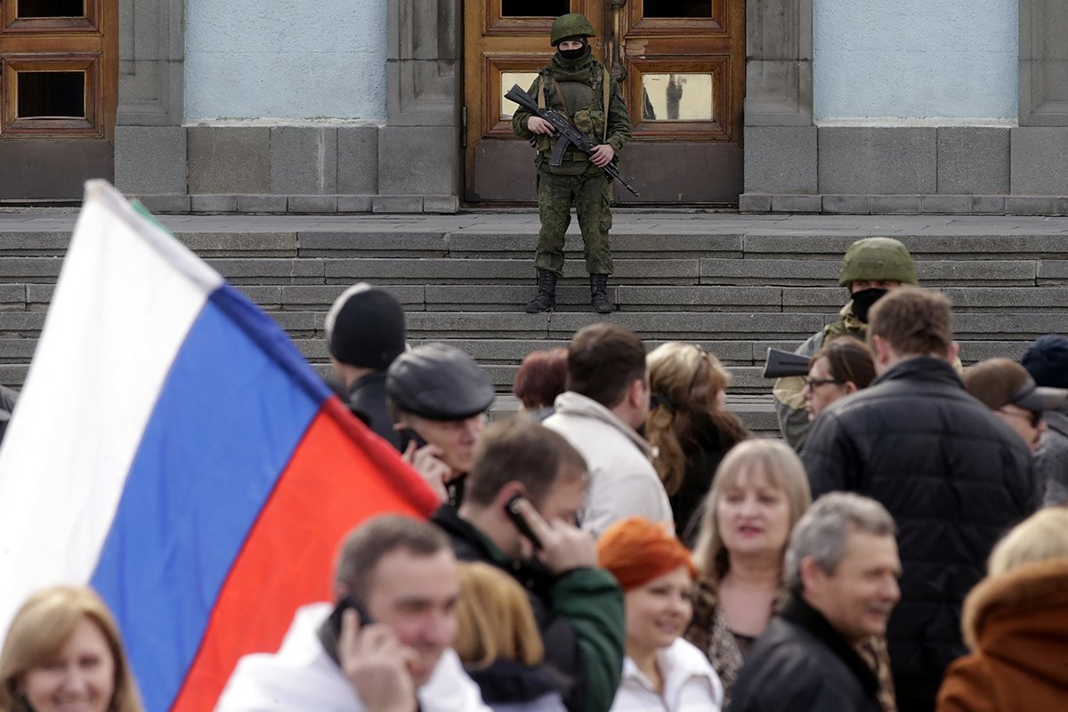 Неопознанный вооруженный человек в военной форме стоит возле входа в здание Кабинета министров Крыма в Симферополе, Украина, 1 марта 2014 года. Фото: Максим Шипенков / EPA