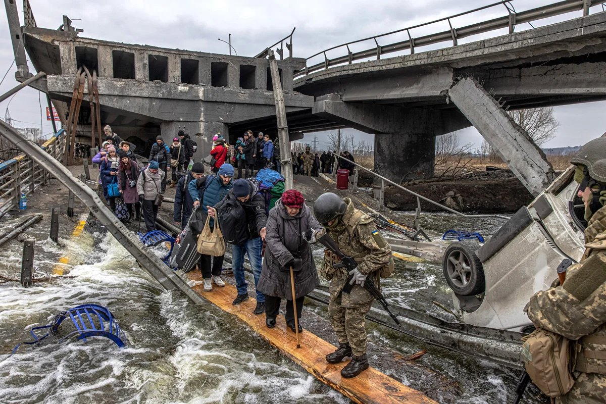 People cross the destroyed bridge as they flee from the frontline town of Irpin ,  7 March 2022. Roman Pilipey / EPA-EFE