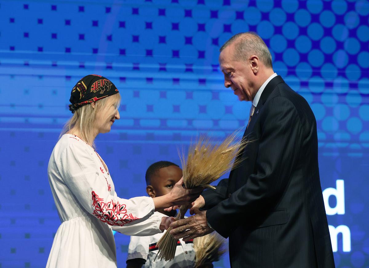Реджеп Эрдоган (справа) получает пучок пшеницы от украинки и африканского ребенка во время Всемирного форума TRT, проводимого на тему «Картирование будущего: неопределенности, реалии и возможности» в Стамбуле, Турция, 9 декабря 2022 года. Фото: Getty Images