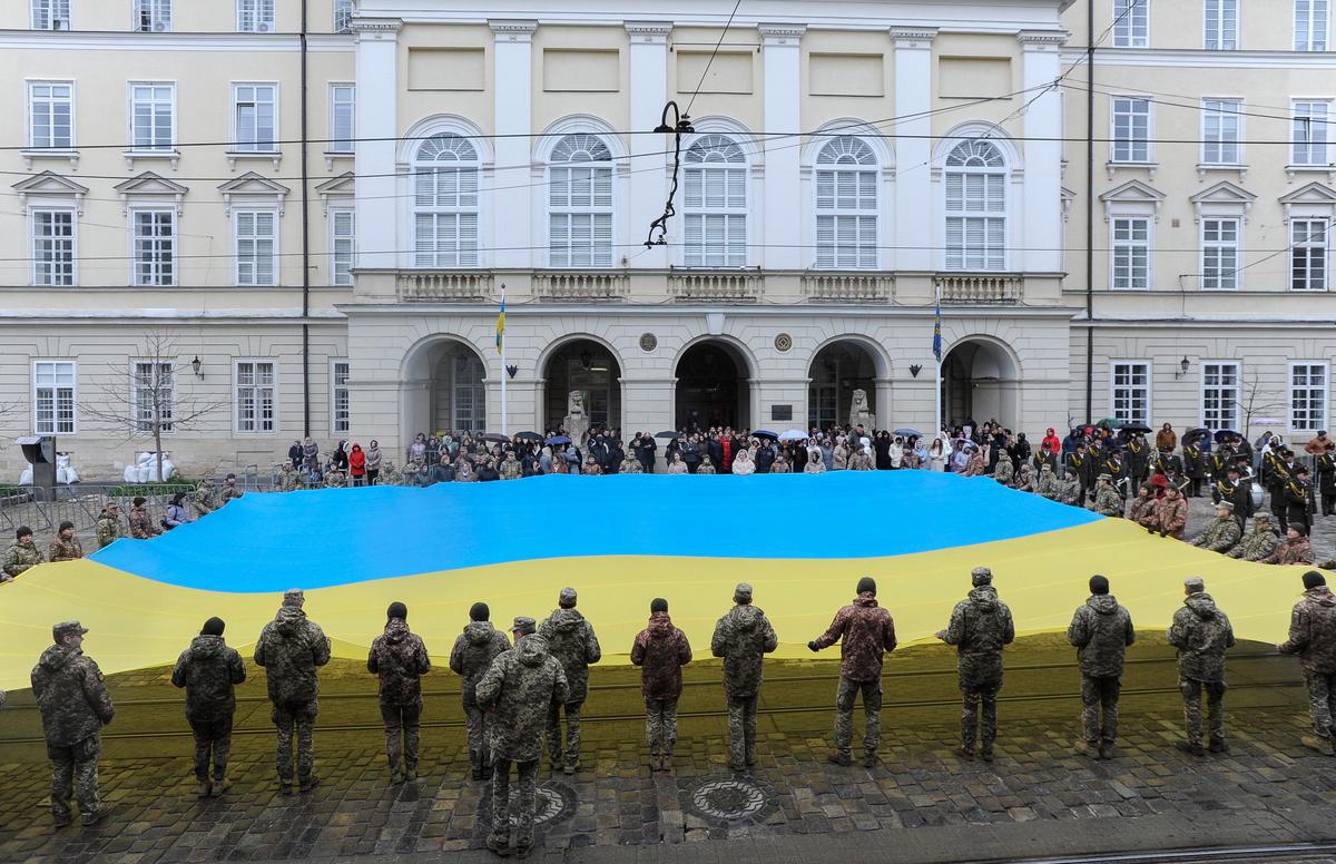 Cadets and civilians hold a large national flag while singing the Ukrainian national anthem in Lviv, western Ukraine, 11 March 2024. Photo: EPA-EFE/MYKOLA TYS