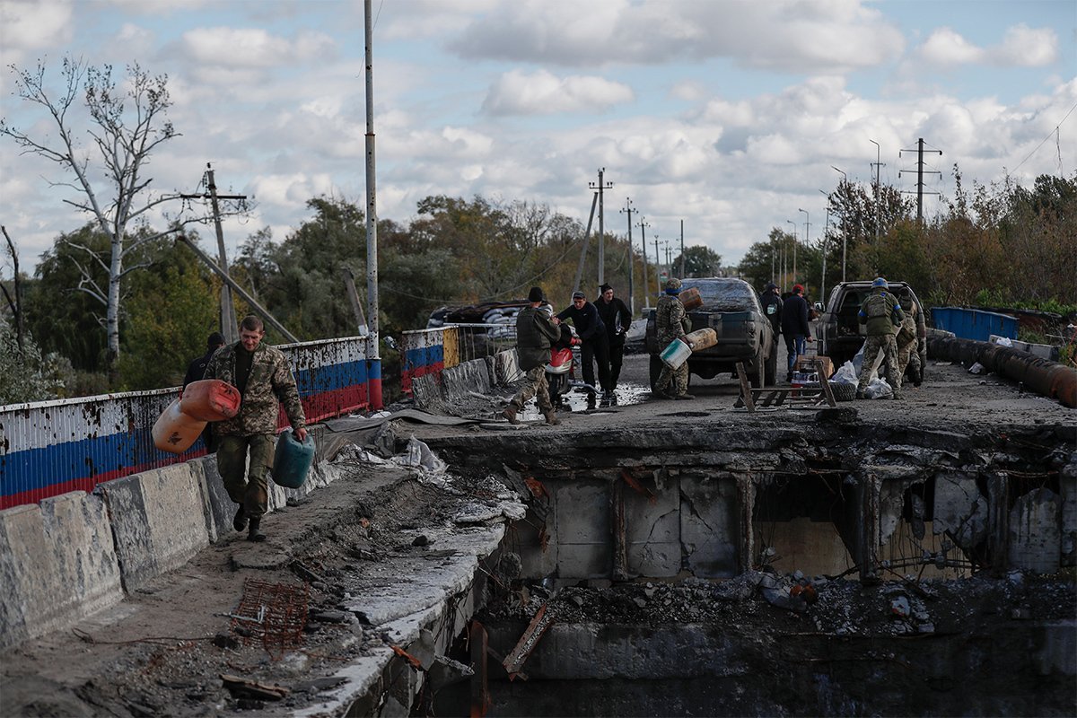 Ukrainian soldiers crossing the remains of a bridge in liberated Kupiansk, a city in the Kharkiv region. October 2022. Photo: Atef Safadi / EPA-EFE