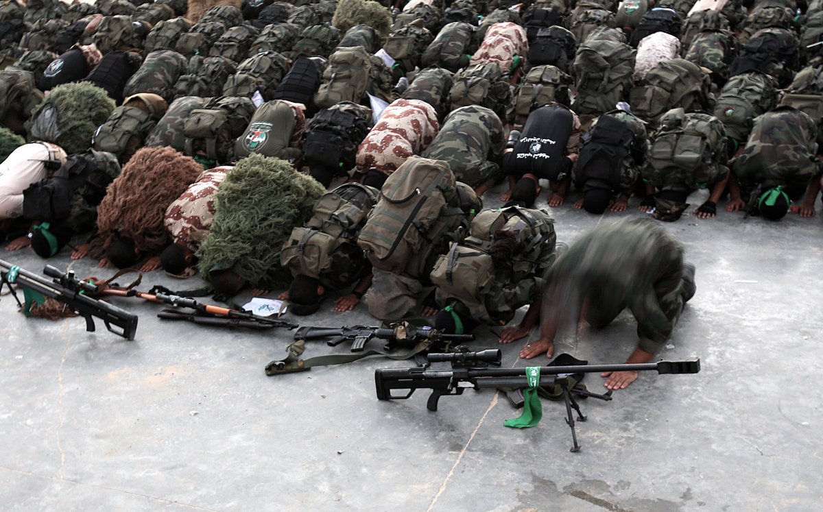Палестинские бойцы ополчения «Эзз аль-Дин аль-Кассам», военного крыла движения ХАМАС, молятся рядом со своим оружием после парада на улицах Бейт-Хануна на севере сектора Газа, 11 августа 2015 года. Фото: Mohammed Saber / EPA