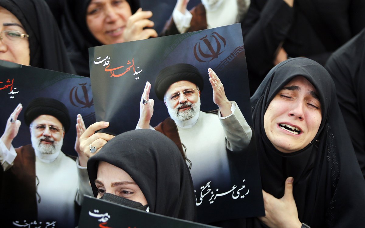 Иранские женщины, одетые в черные чадоры, держат плакаты покойного президента Ирана Эбрахима Раиси во время траурной церемонии в Тегеране, Иран, 20 мая 2024 года. Фото: Abedin Taherkenareh / EPA-EFE