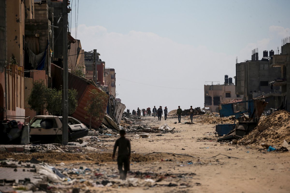 Люди идут среди разрушенных домов, после того, как израильские военные вывели войска из южной части сектора Газа, оставив в этом районе только одну бригаду, 9 апреля 2024 года. Фото: Mohammed Saber / EPA-EFE