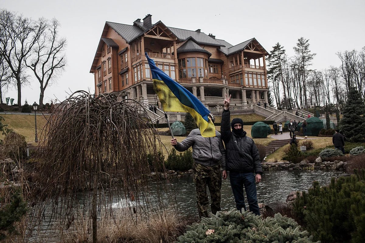 Protesters waving a Ukrainian flag in front of a mansion owned by former President Viktor Yanukovych in Kyiv following his flight from the city, 23 February 2014. Photo: Etienne de Malglaive / Getty Images