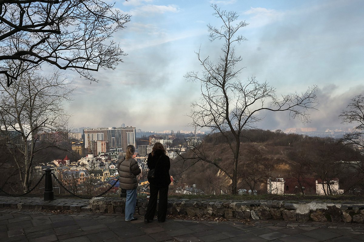 Люди стоят на смотровой площадке на фоне на дыма, поднимающегося над Киевом после обстрела, 29 декабря 2023 года. Фото: Олег Петрасюк / EPA-EFE