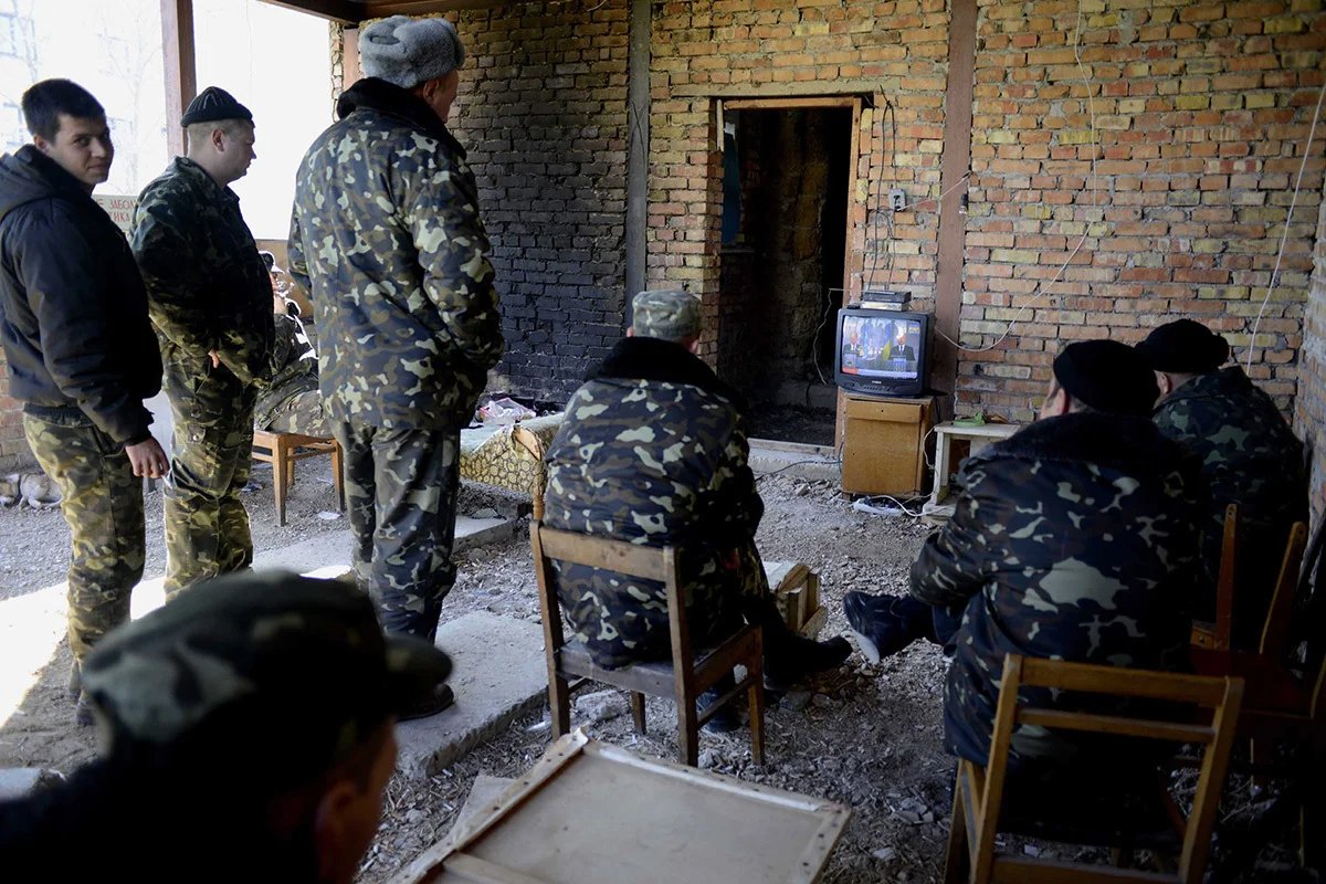 Ukrainian soldiers watch the news on TV as they wait for orders from Kyiv from the Ukrainian military base in Belbek, the last military base that had not surrendered after the annexation of Crimea. 21 March 2014. Photo: EPA/JAKUB KAMINSKI