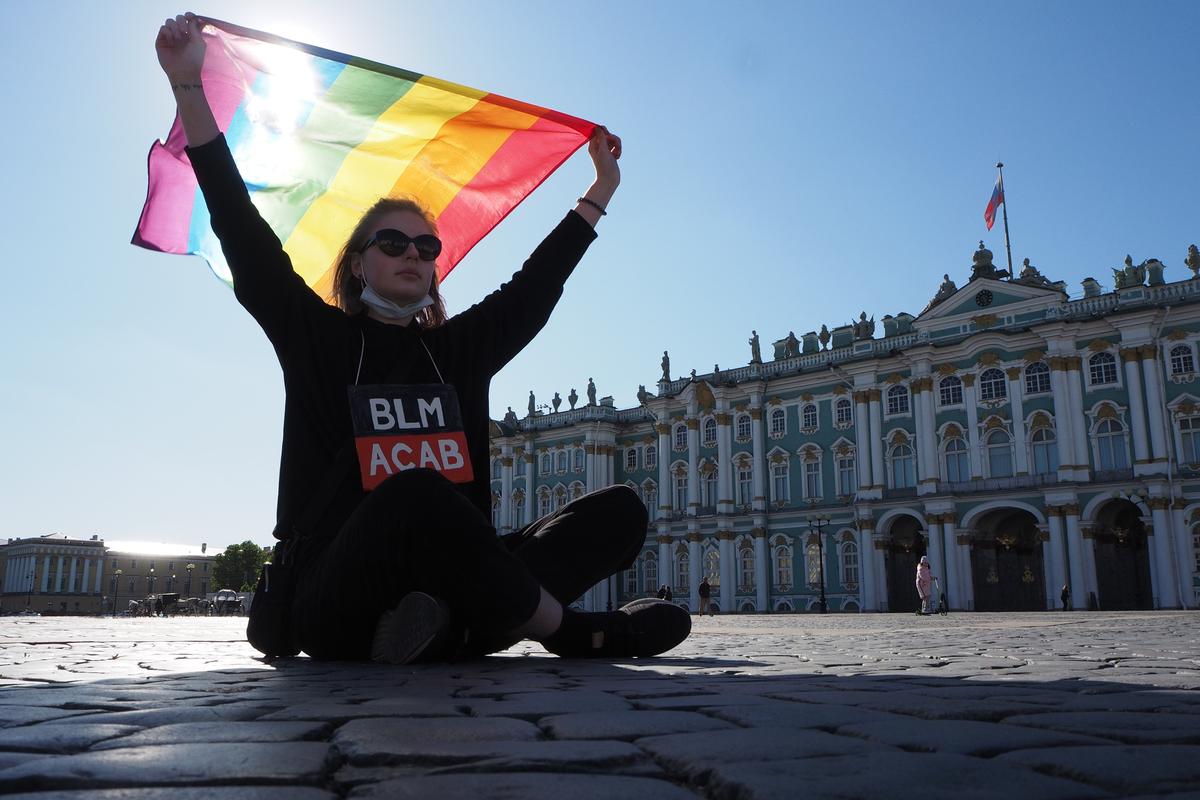 A girl with an LGBTQ+ flag holds a banner saying &quot;BLM ACAB&quot; in a protest against US police violence, St. Petersburg, Russia, on June 1, 2020. Photo by Sergey Nikolaev/NurPhoto via Getty Images
