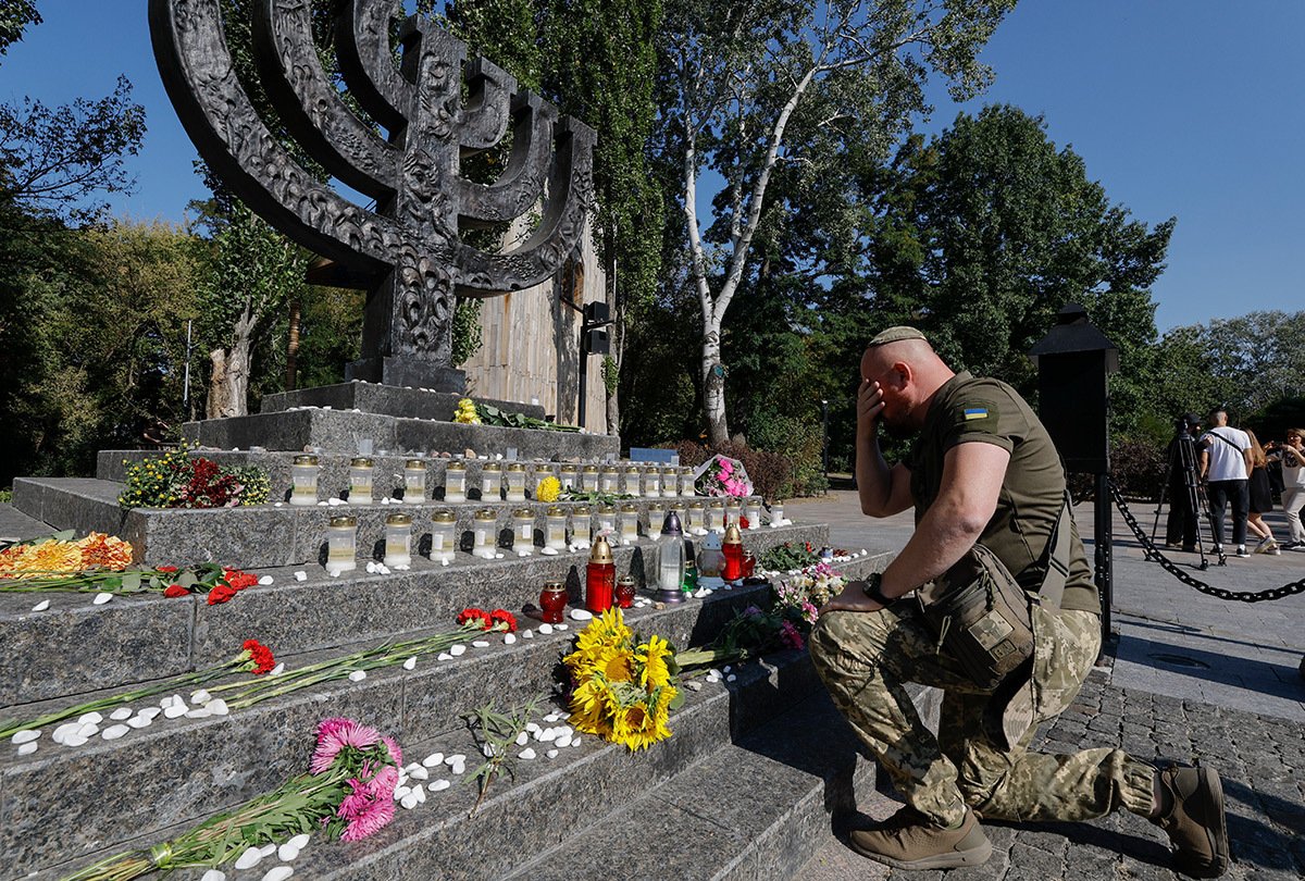 Еврейский украинский солдат стоит перед памятником Меноре во время церемонии памяти на месте Бабьего Яра в Киеве, 29 сентября 2023 года. Фото: Сергей Долженко / EPA-EFE