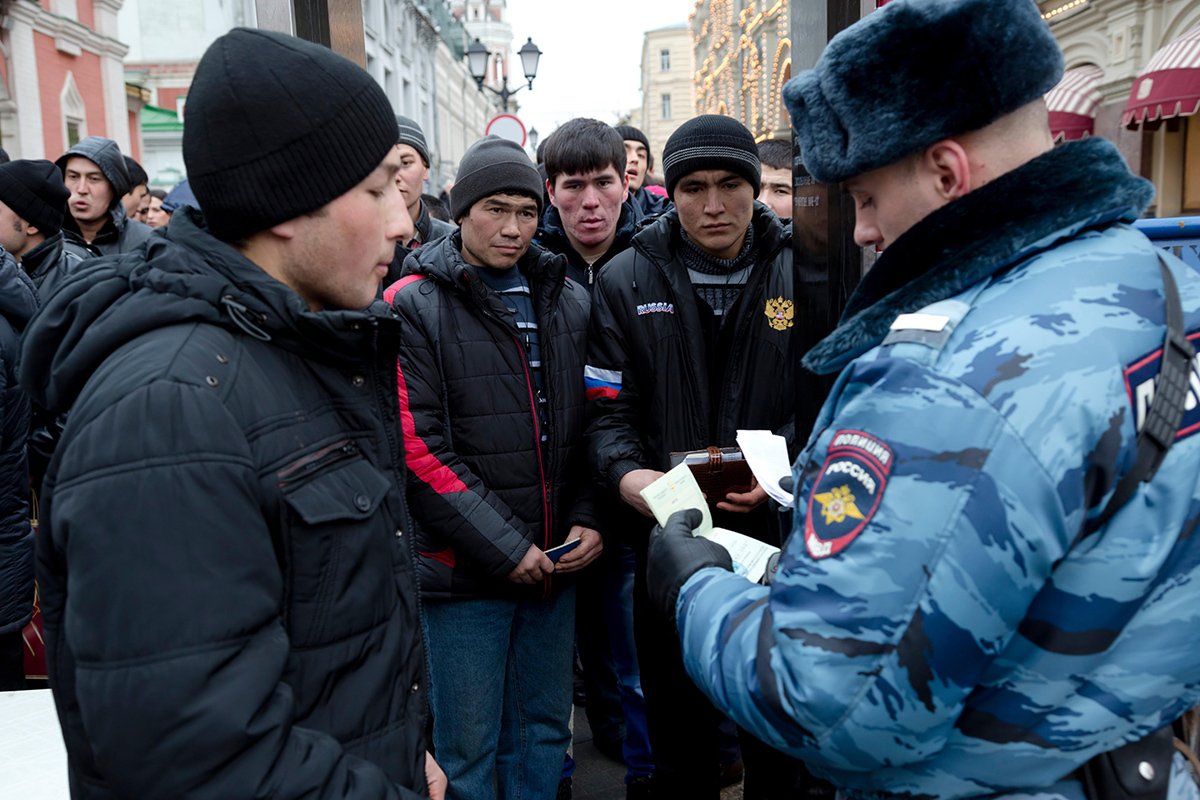 Полицейский проверяет документы у мигрантов из Средней Азии около Красной площади в Москве, 31 декабря 2013 года. Фото: Николай Винокуров / Alamy / Vida Press