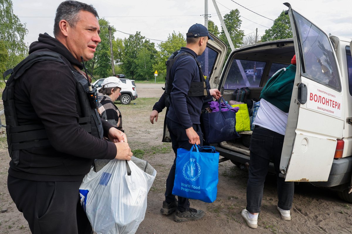 Полицейские помогают местным жителям погрузить вещи в автобус во время эвакуации с приграничных территорий на окраине Волчанска, Харьковская область, 12 мая 2024 года. Фото: Сергей Козлов / EPA-EFE