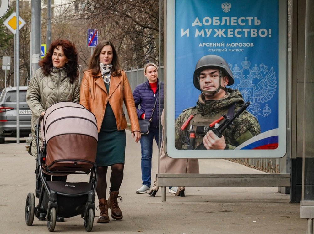 Women walk past an advertisement for military conscription in Moscow. Photo: EPA-EFE/YURI KOCHETKOV