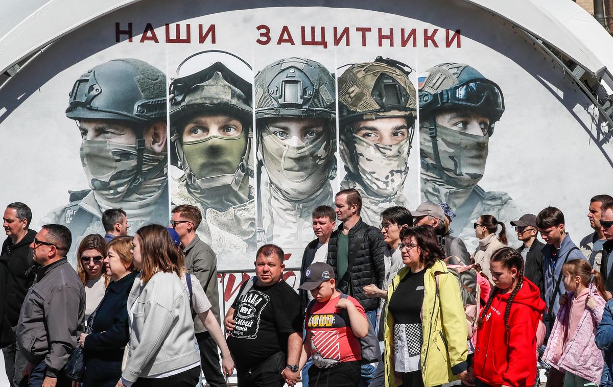 Люди стоят возле изображений российских солдат и надписи «Наши защитники» на выставке оружия, захваченного российской армией в Украине, на Поклонной горе в Москве, 1 мая 2024 года. Фото: EPA-EFE/ЮРИЙ КОЧЕТКОВ