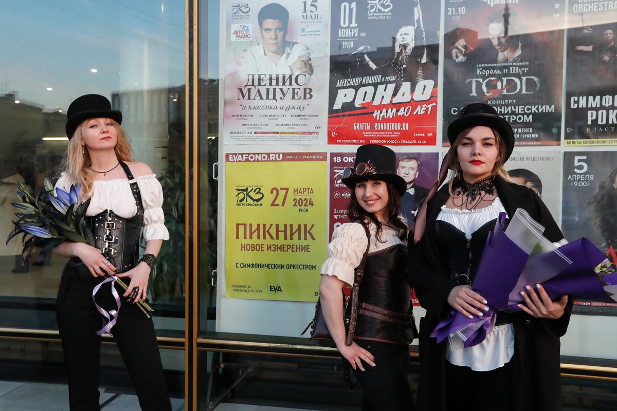 Поклонники группы «Пикник» фотографируются с плакатом у концертного зала «Октябрьский» в Санкт-Петербурге, 27 марта 2024 года. Фото: Анатолий Мальцев / EPA-EFE