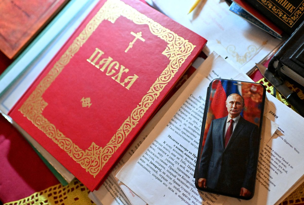 Телефон священника в чехле с изображением Владимира Путина на столе перед пасхальной службой в церкви, Омская область, 19 апреля 2025 года. Фото: Алексей Малгавко / Reuters / Scanpix / LETA