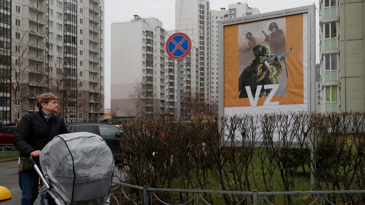 A woman walks past a military propaganda poster in St. Petersburg, 25 April 2022. Photo: Anatoly Maltsev / EPA-EFE