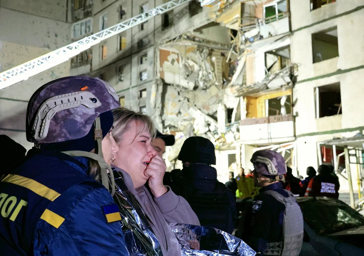 A local woman is comforted by rescue workers following a strike on a damaged nine-storey residential building in Kharkiv, 30 October 2024. Photo: Sergey Kozlov / EPA-EFE