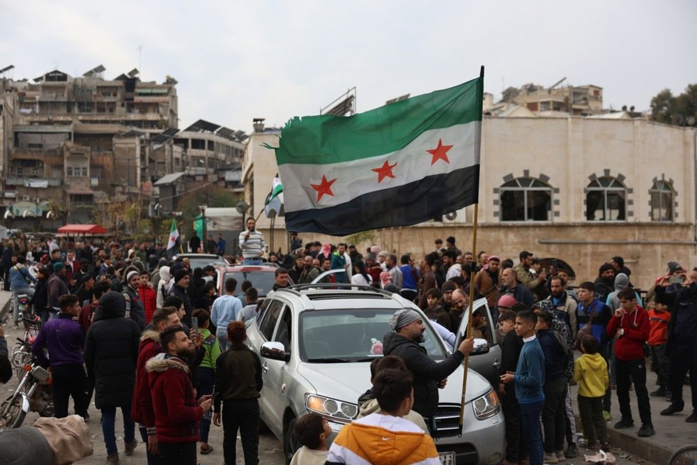 People wave a Syrian opposition flag after opposition fighters took control of the city of Hama, Syria, 7 December 2024. Photo: EPA-EFE/MOHAMMED AL RIFAI