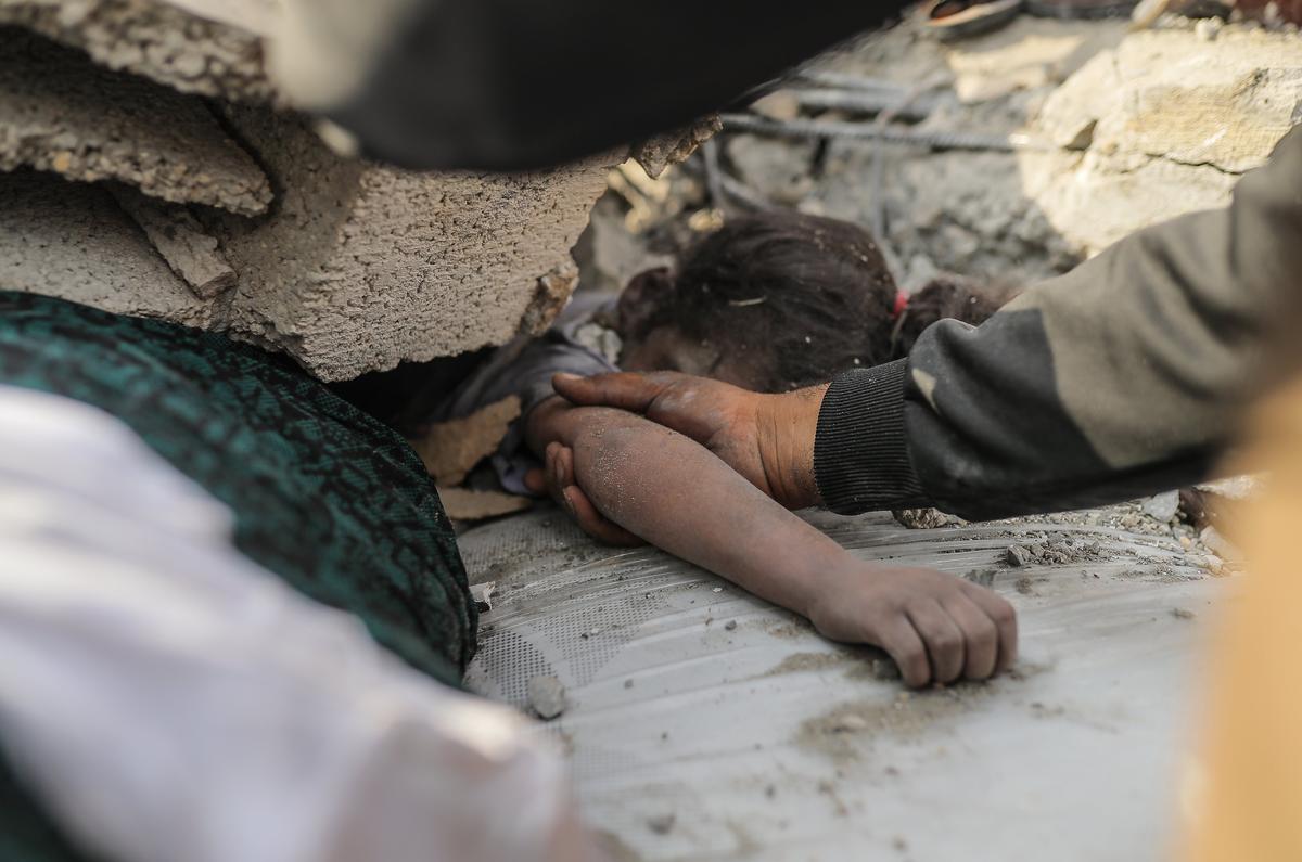 Спасатель достает труп маленькой девочки из-под завалов после израильских авиаударов по городу Газа, Газа, 9 октября 2023 года. Фото Белала Халеда / Getty Images