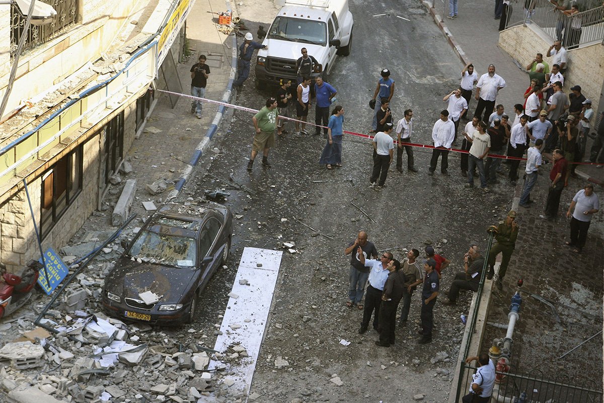Люди собрались на месте падения ракеты типа «Катюша», выпущенной с территории соседнего Ливана, 13 июля 2006 г. в городе Цфат. Фото: Uriel Sinai / Getty Images