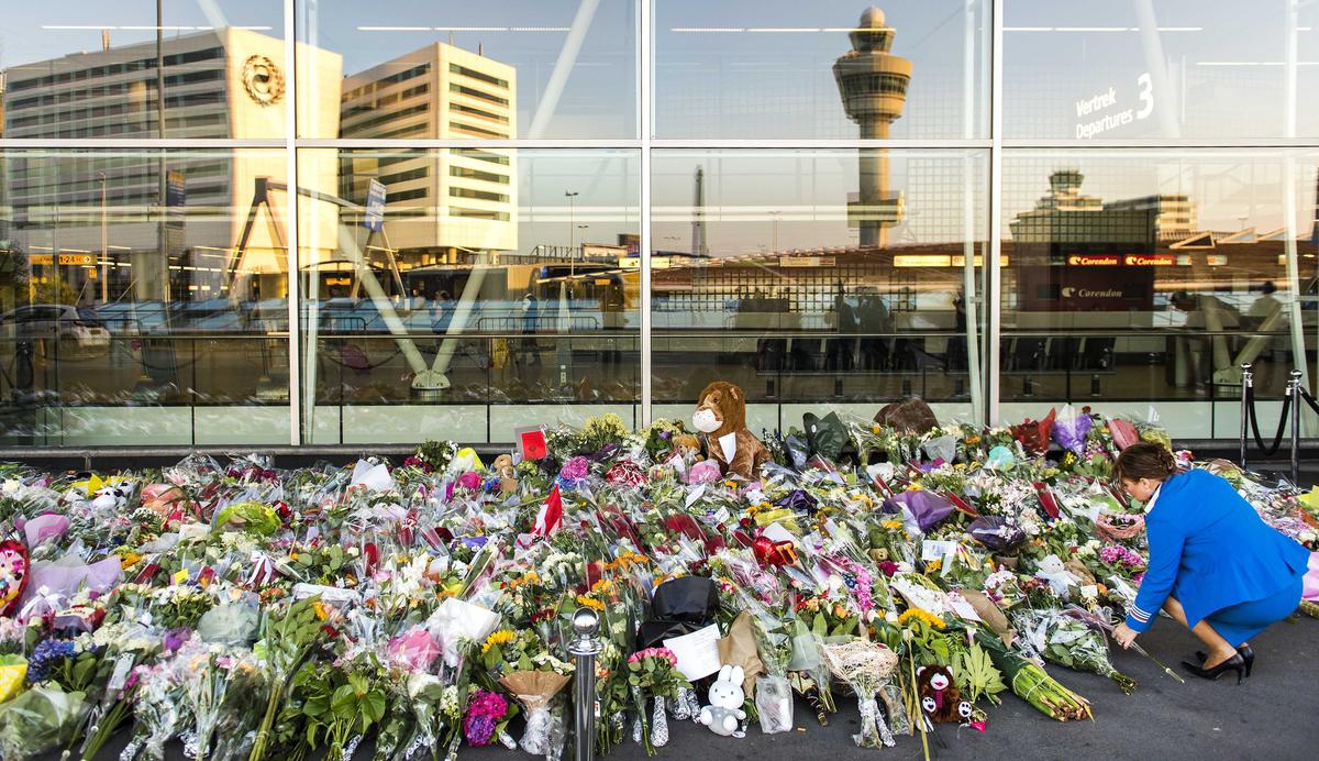 A woman arranges floral tributes to the victims of the MH17 tragedy outside Amsterdam’s Schiphol Airport, the Netherlands, 24 July 2014. Photo: EPA / REMKO DE WAAL