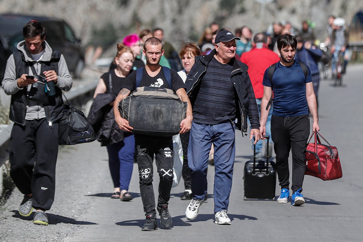 Россияне с багажом идут по дороге после прохождения таможенного контроля на грузино-российском пограничном пункте Верхний Ларс, 27 сентября 2022 года. Фото: Зураб Курцикидзе / EPA-EFE