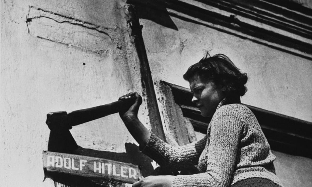 Жительница Одессы снимает табличку с названием улицы, переименованной во время фашистской оккупации города. Фото: Марк Редькин, 24 апреля 1944 г., из собрания агентства «ФотоСоюз»