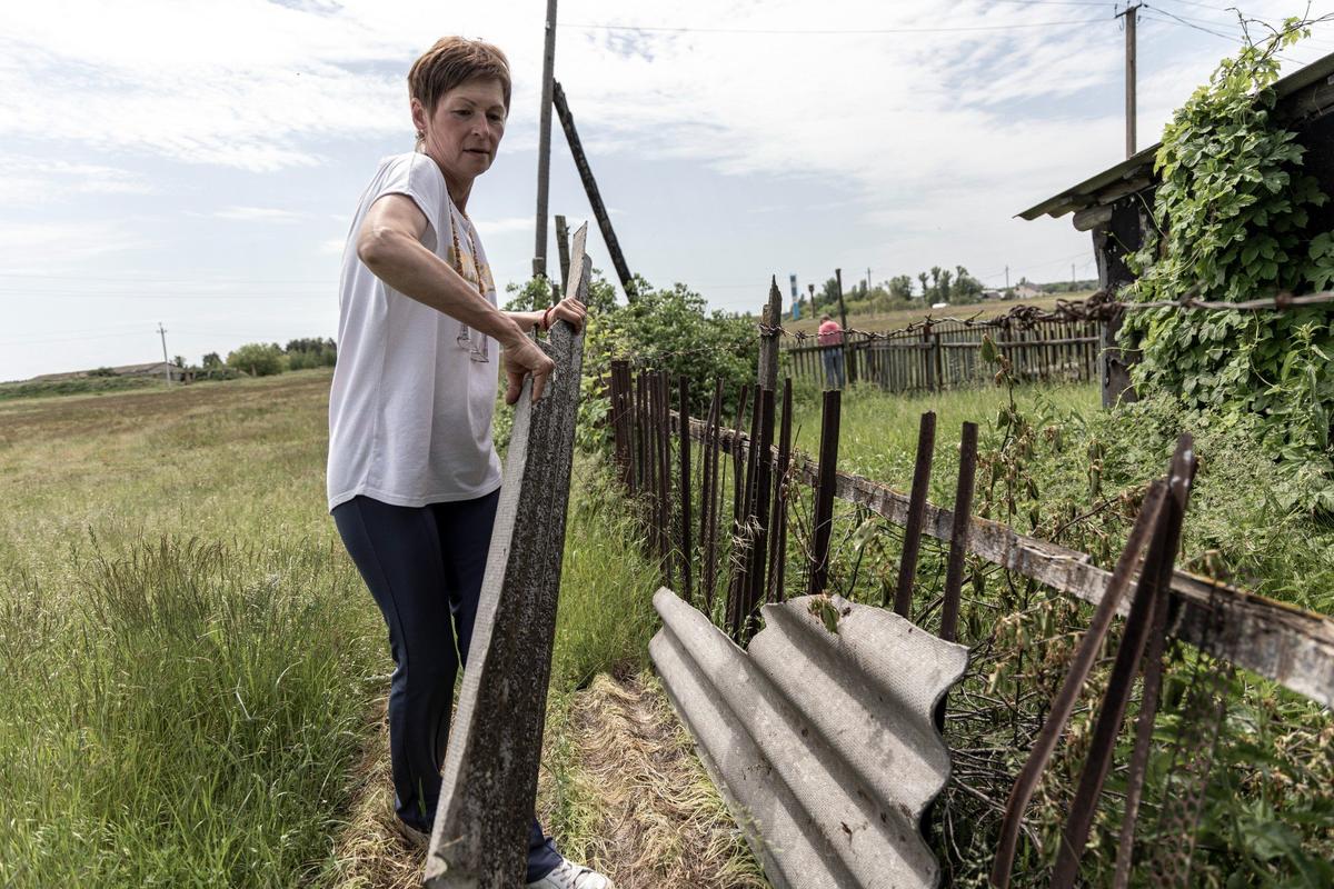 Ирина из подручных средств восстанавливает забор, чтобы собаки не убегали. Фото: Арден Аркман
