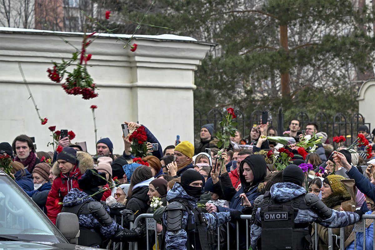 Пришедшие проститься с Алексеем Навальным бросают цветы на автобус, в котором увозят тело Навального из церкви на кладбище. Фото: Stringer / Anadolu / Getty Images