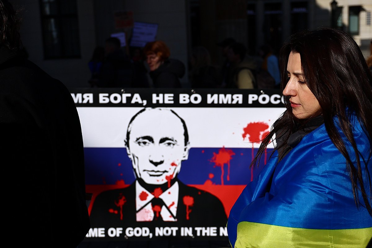 Një pjesëmarrës në një tubim në Berlin qëndron përpara një pankarte me një deklaratë kundër Vladimir Putin, Gjermani, 24 shkurt 2024.  Foto: Filip Singer/EPA-EFE