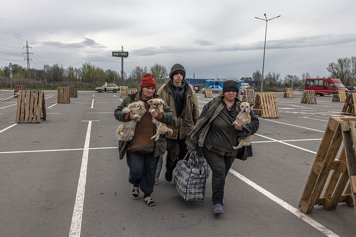Мать (слева) из оккупированного Россией поселка Мирное, который находится недалеко от Мелитополя, со своими двумя взрослыми детьми и собаками после прибытия в пункт эвакуации в Запорожье, Украина, 23 апреля 2022 года. Фото: Роман Пилипей/EPA-EFE