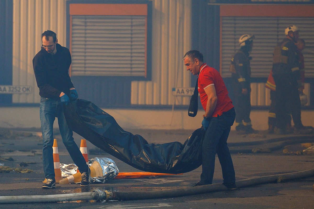 Люди несут тело человека, погибшего в результате российского авиаудара по торговому центру, Харьков, Украина, 25 мая 2024 года. Фото: Valentyn Ogirenko / Reuters / Scanpix / LETA