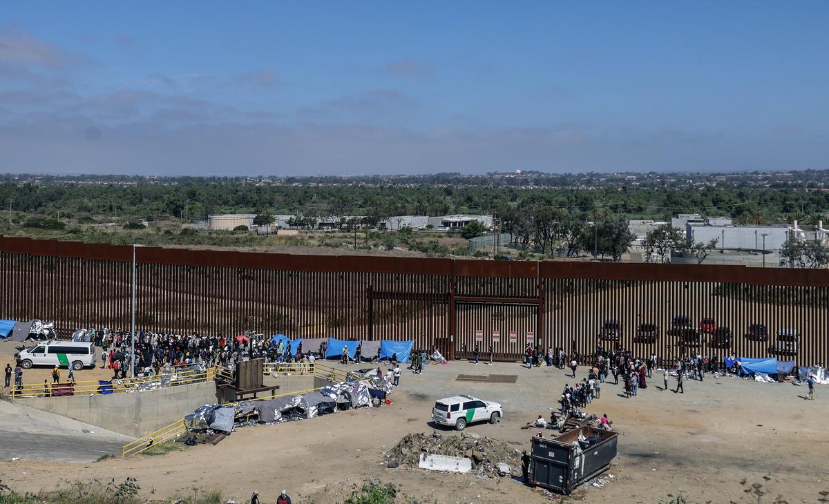 Мигранты стоят рядом с пограничным забором в городе Тихуана, Нижняя Калифорния, Мексика, 13 сентября 2023 г. Фото: ДЖОБЕТ ТЕРРИКИС / EPA-EFE