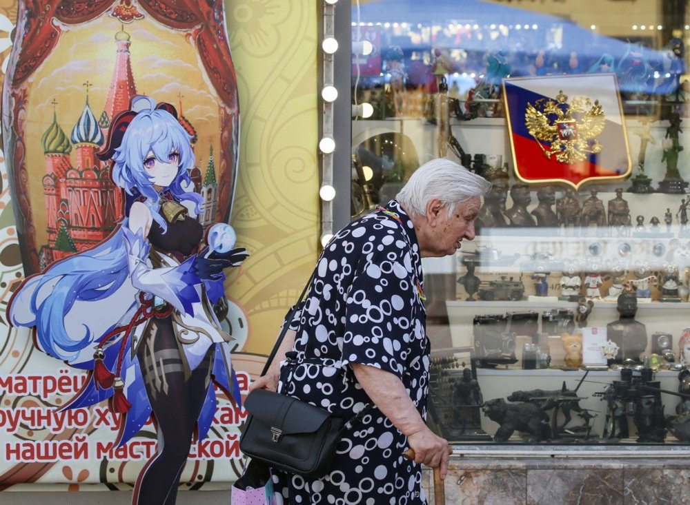 An elderly woman walks past a cardboard depicting an anime character near a shop window in Moscow, 7 June 2024. EPA-EFE/YURI KOCHETKOV