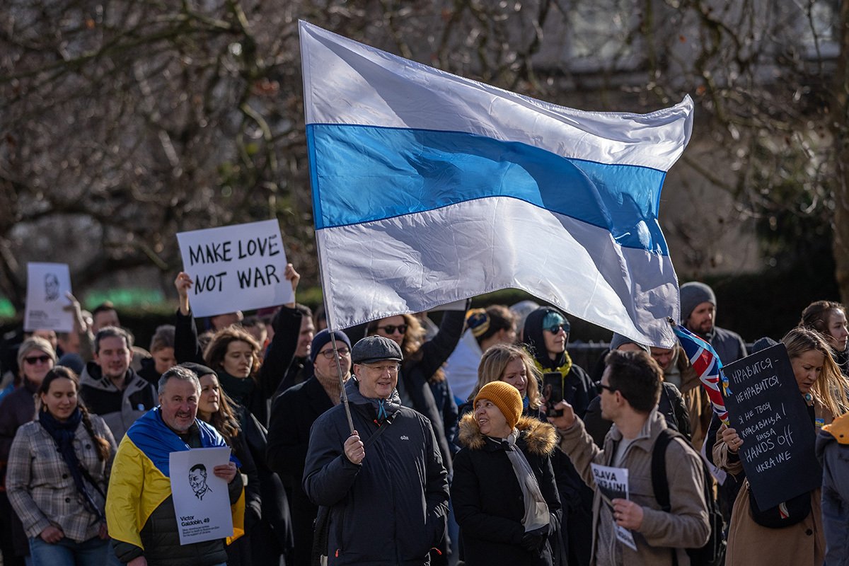 Мужчина держит сине-белый флаг во время марша в честь первой годовщины российского вторжения на Украину, 25 февраля 2023 года, Лондон. Фото: Carl Court / Getty Images