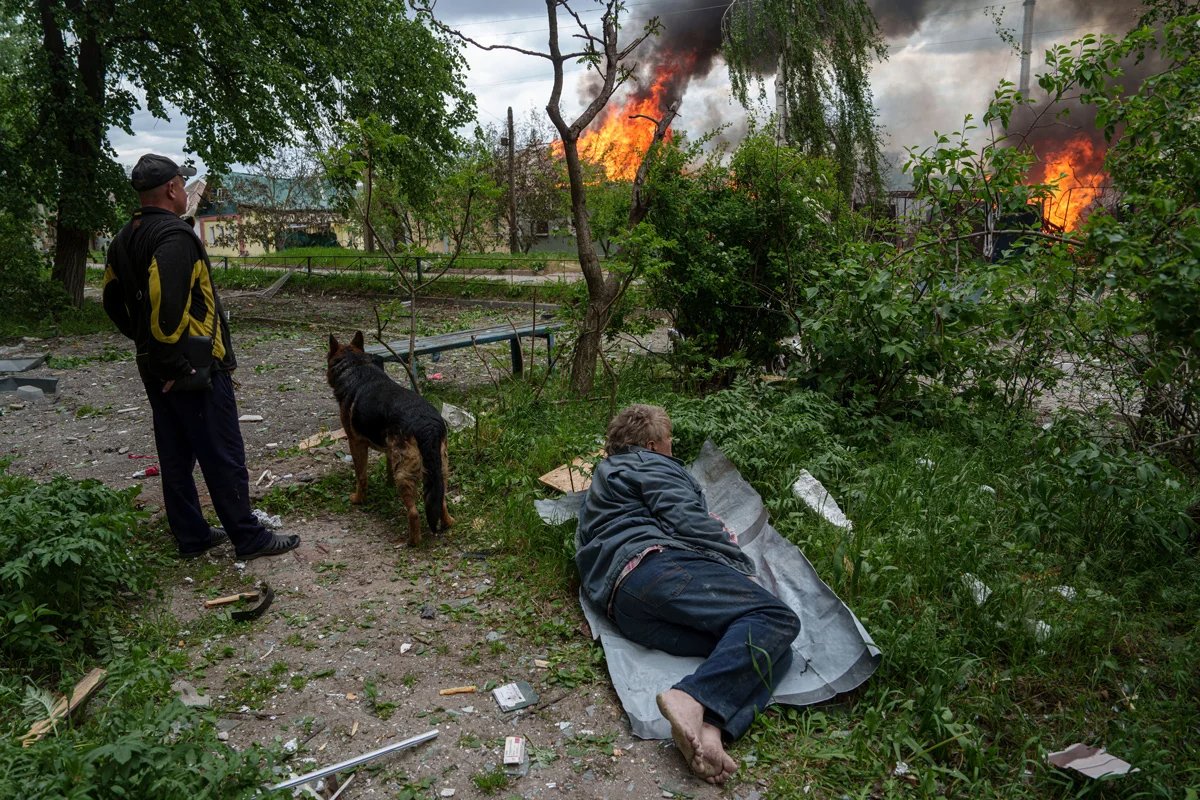 A man lies on the ground watching as his house is destroyed in a Russian airstrike. Vovchansk, Ukraine, 11 May 2024. Photo: Evgeniy Maloletka / AP Photo / Scanpix