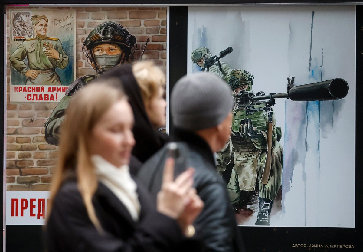 Прохожие на фоне выставки военных плакатов «Вместе к Победе», созданных художниками и посвященных российским солдатам, Санкт-Петербург, 30 ноября 2024 года. Фото: Анатолий Мальцев / EPA-EFE