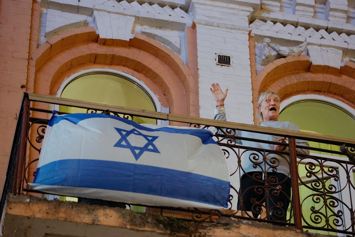 Пожилая женщина вывешивает израильский национальный флаг на своем балконе в центре Киева, Украина, 8 октября 2023 года. Фото: Сергей Долженко / EPA-EFE