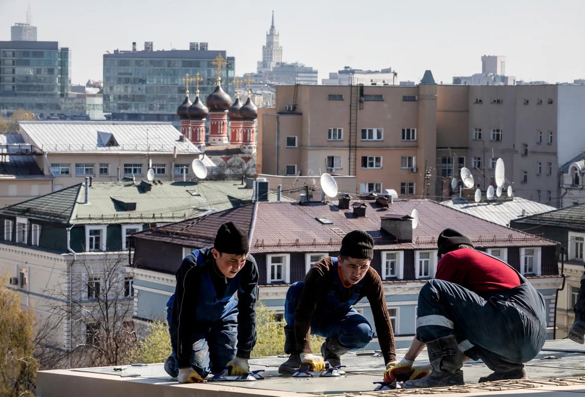 Central Asia migrant workers repair a roof on a Moscow office building. Photo: Nikolay Vinokurov / Alamy / Vida Press