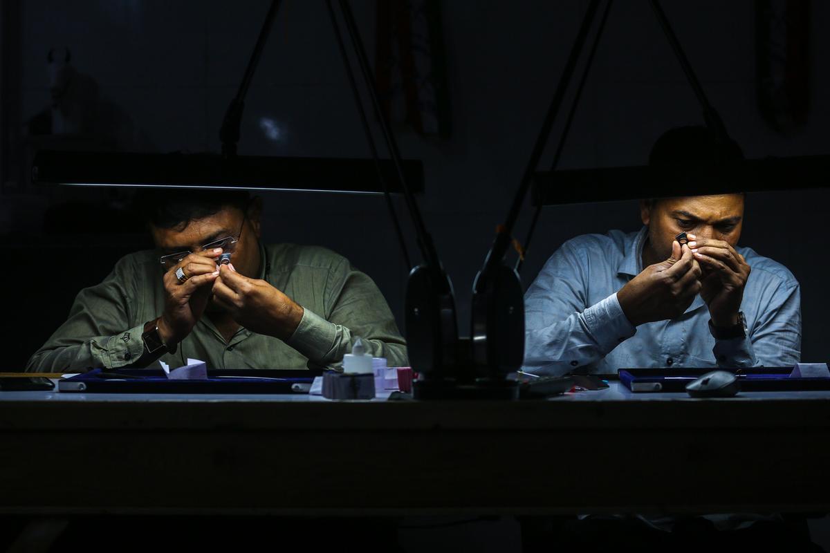 Сотрудники осматривают бриллианты в мастерской на алмазном рынке в городе Сурат на западе Индии, где ограняется и полируется 80% алмазов в мире, Индия, 2 октября 2023 г. Фото: Дивянкани Соланки/EPA-EFE