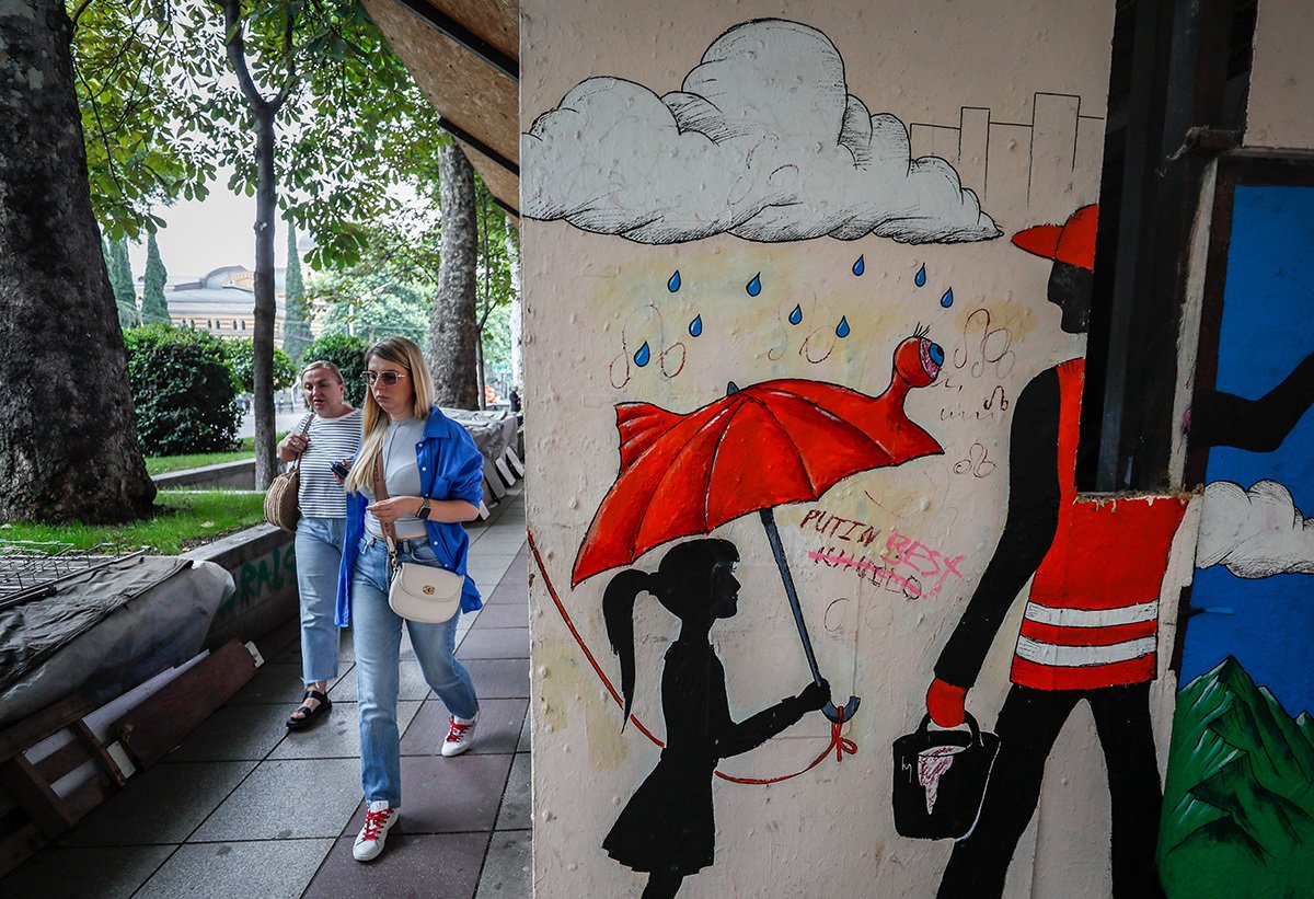 Женщины проходят мимо антивоенного граффити на стене здания в Тбилиси, Грузия, 20 июня 2023 года. Фото: Юрий Кочетков / EPA-EFE