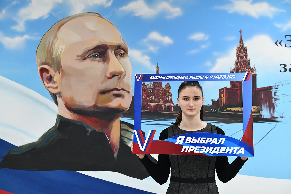 Женщина позирует с портретом Владимира Путина после голосования на президентских выборах на избирательном участке в Донецке, контролируемой Россией части Украины, 15 марта 2024 года. Фото: Стрингер / EPA-EFE
