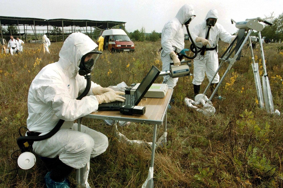 Французские ученые в защитных костюмах и противогазах измеряют и анализируют уровень радиоактивности примерно в 6 км от Чернобыльской АЭС, 15 сентября 1999 года. Фото: Сергей Супинский / EPA