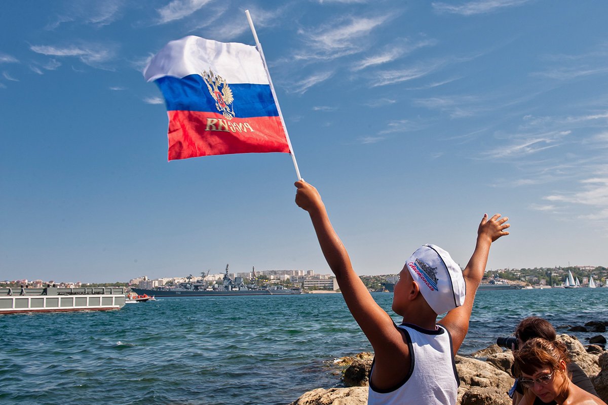 Мальчик размахивает российским флагом во время парада в честь Дня Военно-морского флота России, Севастополь, Крым, Украина. Фото: Антон Педько / EPA