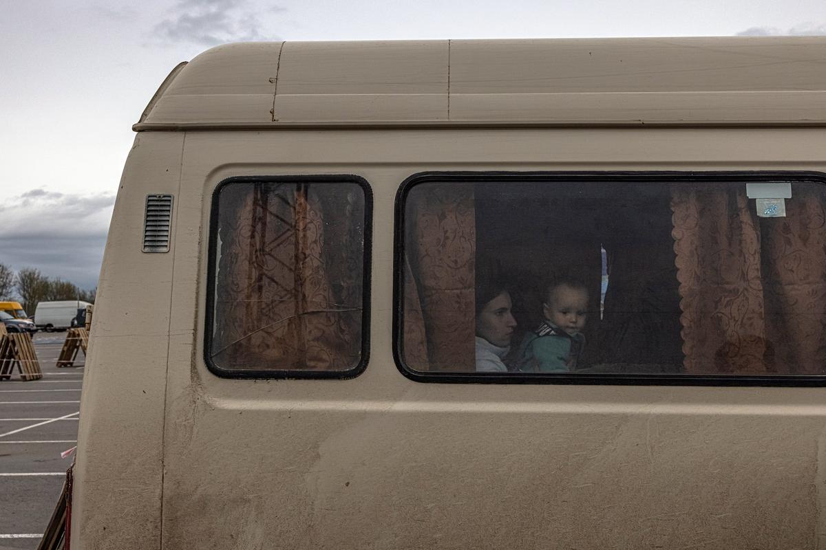Ребенок выглядывает из микроавтобуса после прибытия из портового города Геническ, Херсонской области. Фото: Роман Пилипей / EPA-EFE