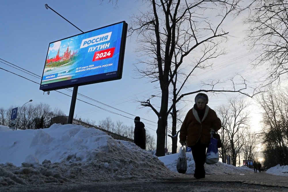 People walk in front of a pre-election campaign billboard reading “Russia Putin 2024” in Moscow, 22 January. Photo: EPA-EFE/MAXIM SHIPENKOV