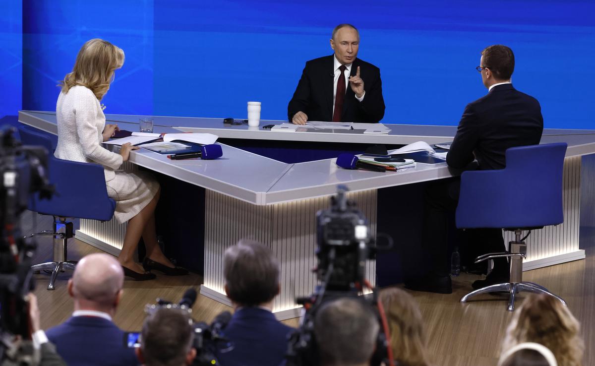 Putin answers questions as presenters Pavel Zarubin and Yekaterina Berezovskaya look on. Photo: EPA / SERGEI ILNITSKY
