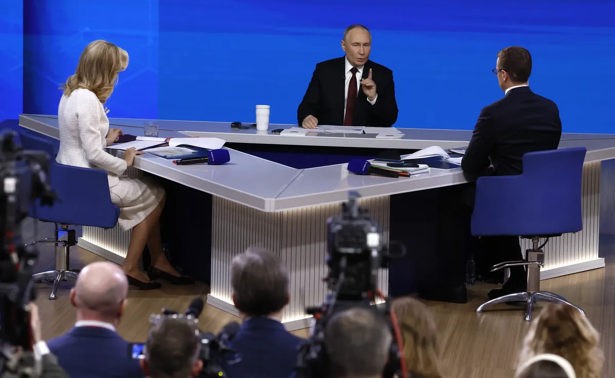 Putin answers questions as presenters Pavel Zarubin and Yekaterina Berezovskaya look on. Photo: EPA / SERGEI ILNITSKY